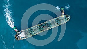 Aerial top view oil tanker ship at terminal industrial port tugboat drag crude oil tanker ship park to port for transfer crude oil