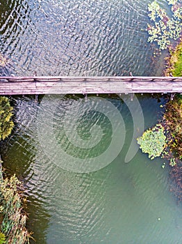 Aerial top view of old wooden bridge over cold pond