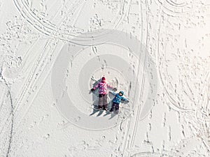 Aerial top view pair two cute little sibling kids boy girl have fun play make snow angel on white frozen lake ice