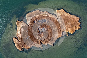 Aerial top view of a patch of brown grass in a salt marsh on a sunny day