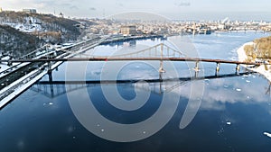 Aerial top view of pedestrian and cycling path lane on Park bridge in winter and Dnieper river from above, city of Kyiv Kiev