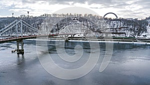 Aerial top view of pedestrian Park bridge in winter and Dnieper river from above, snow Kyiv cityscape, city of Kiev skyline