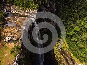 Aerial top view perspective of amazing 500 feet tall waterfall in the tropical island jungle of Mauritius.