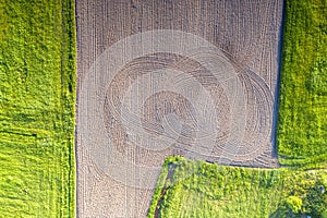 Aerial top view photo of fresh green spring and just plowed soil fields. Tractor tracks, no people