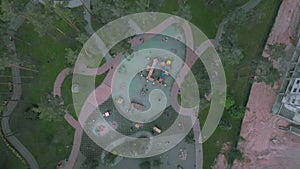 Aerial top view of playground with swings and carousels in city park. Child playground with children playing around. Drone flying