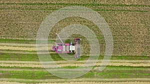 Aerial top view red harvester machine working in fields. The harvesting process. Agriculture food production.