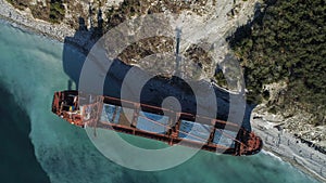 Aerial top view of red industrial ship with people on board doing sailor work moored near sea shore. Shot. Big barge on