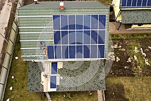 Aerial top view of residential house with team of workers installing solar photo voltaic panels system on roof. Renewable energy