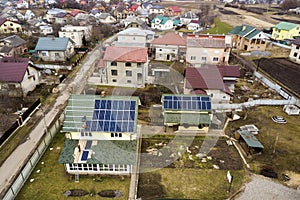 Aerial top view of residential house with team of workers installing solar photo voltaic panels system on roof. Renewable energy