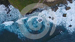 Aerial top view of rocks and blue ocean waves in Bali