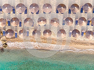 Aerial top view of sandy beach and turquoise sea, with umbrellas and sun loungers in Beautiful sunny