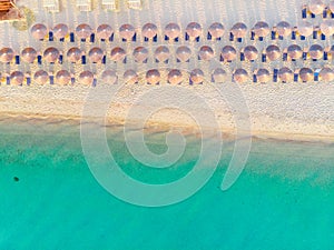 Aerial top view of sandy beach and turquoise sea, with umbrellas and sun loungers in Beautiful sunny summer