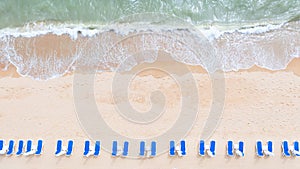 Aerial top view on the sandy beach. Umbrellas, sand, beach chairs and sea waves
