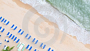 Aerial top view on the sandy beach. Umbrellas, sand, beach chairs and sea waves