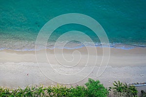 Aerial top view of sea waves crashing against the sandy empty beach