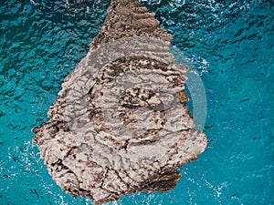 Aerial top view of sea waves hitting rocks.