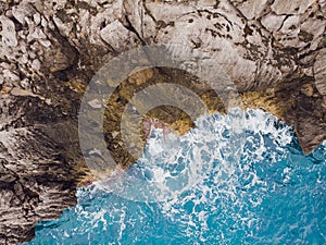 Aerial top view of sea waves hitting rocks.