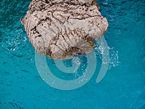 Aerial top view of sea waves hitting rocks.