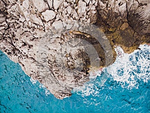 Aerial top view of sea waves hitting rocks.