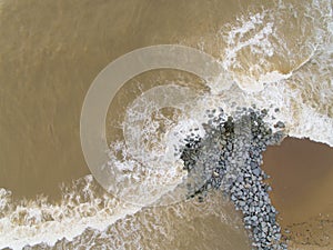 Aerial top view of sea waves hitting rocks on the beach in Pantai cahaya bulan photo