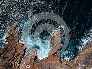 Aerial top view of sea waves hitting rocks on the beach with turquoise sea water. Amazing rock cliff seascape in the Portuguese co