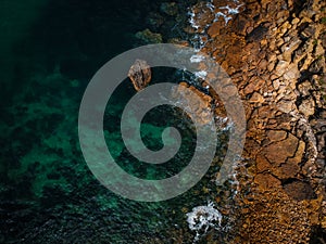 Aerial top view of sea waves hitting rocks on the beach with turquoise sea water. Amazing rock cliff seascape in the Portuguese co