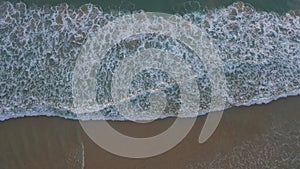 Aerial top view sea waves seamless loop on the white sand beach.
