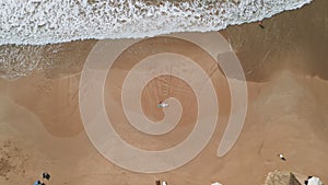 Aerial top view of slender woman in pink bikini lying on sandy shore with surfboard. Pretty surfer girl relax after