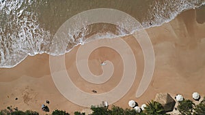 Aerial top view of slender woman in pink bikini lying on sandy shore with surfboard. Pretty surfer girl relax after