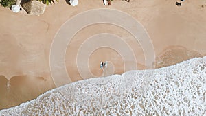 Aerial top view of slim guy and girl in dark swimsuits lying on sand shore with surfboards next to them. Romantic surfer