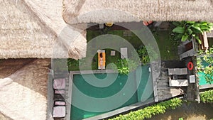 Aerial top view of slim young woman in beige bikini relaxing and get sunbathe near swimming pool in chaise-longue in