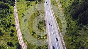 Aerial top view of summer green trees, river, roads in forest background. Aerial view of crooked path of road on the