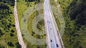 Aerial top view of summer green trees, river, roads in forest background. Aerial view of crooked path of road on the