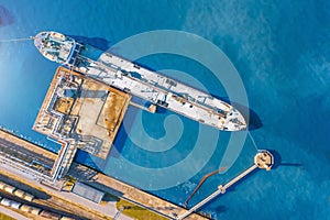 Aerial top view tanker at unloading in a large bulk port liquid cargo, oil, liquefied gas, fuel