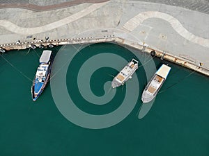 Aerial top view of three white moored boats or yachts at pier, view from above. Copy space
