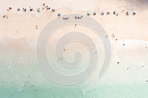 Aerial top view tourist playing in the sea on vacation and umbrella on the beach, summer holiday concept