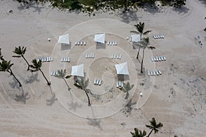 aerial top view of tropical white sand beach with palms, sun lounger and parasol