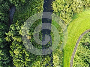Aerial top view, walking path in a park by a small creek and trees