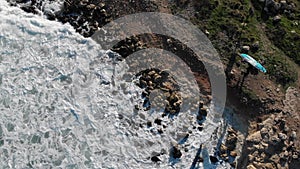 Aerial top view waves break on rocks in a blue ocean from above. Drone spinning around from top view sea waves 4k shot