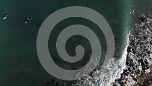 Aerial top view waves break on rocks in a blue ocean. Drone spinning around from top view sea waves 4k shot. Bird's eye