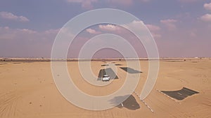 AERIAL. Top view of white car driving on the deserts road after sandstorm.