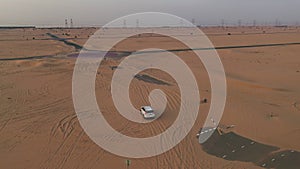 AERIAL. Top view of white car driving on the deserts road after sandstorm.