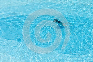 Aerial top view on the woman in the swimming pool with transparent blue water.