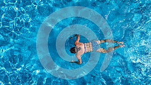 Aerial top view of woman in swimming pool water from above, tropical vacation holiday