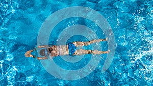 Aerial top view of woman in swimming pool water from above, tropical vacation holiday