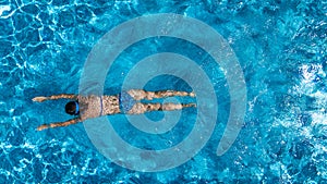 Aerial top view of woman in swimming pool water from above, tropical vacation concept