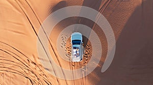 AERIAL. Top view of young couple relaxing on the car's roof at the desert.