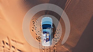 AERIAL. Top view of young couple relaxing on the car's roof at the desert.