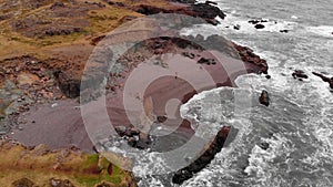 Aerial top view of the young man walking on the shore of the sea in beach in Iceland and enjoying the water.