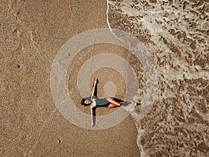 Aerial top view young woman lying on the sand beach and waves